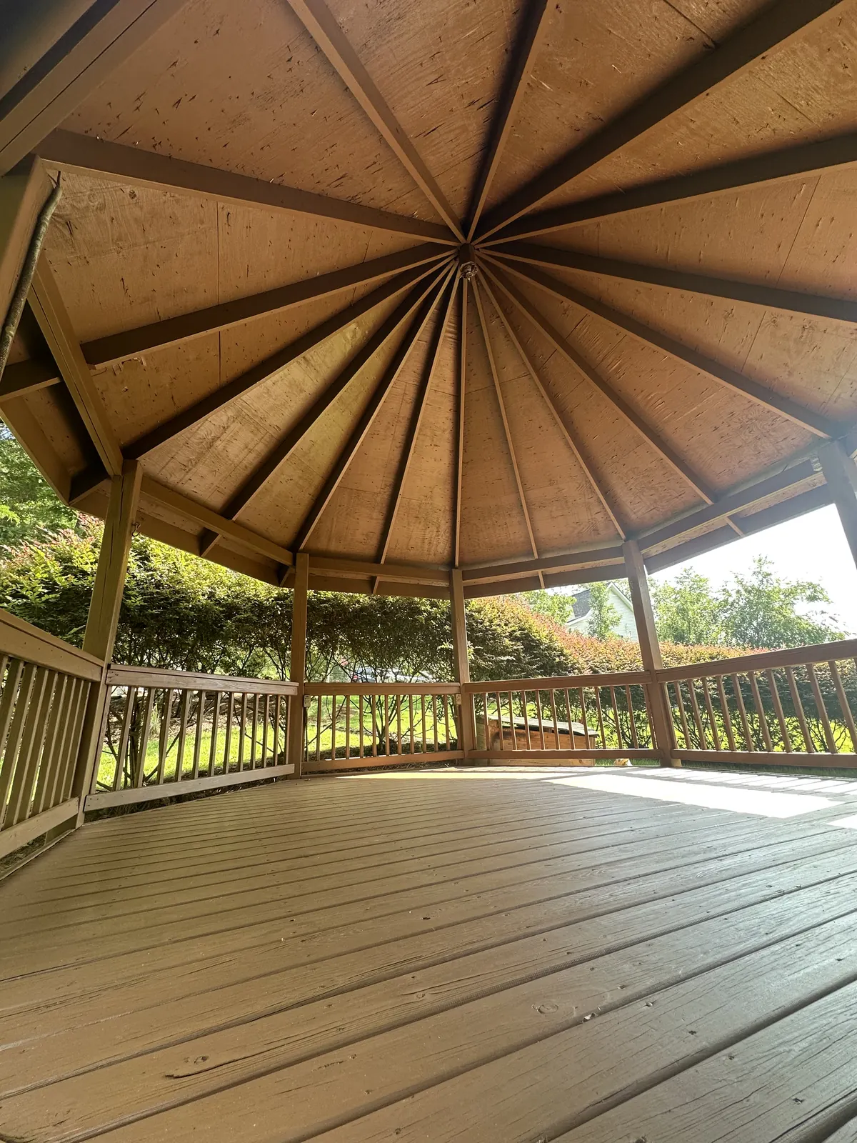 Freshly stained wooden gazebo with railings and floor