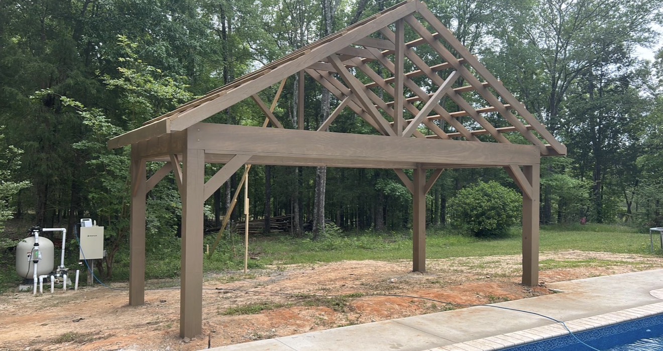 Wooden pavilion with freshly finished beams beside a pool